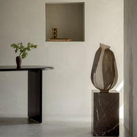 Elegant ceramic vase with beige and brown stripes, paired with a dark marble pedestal, in a minimalist interior setting.
