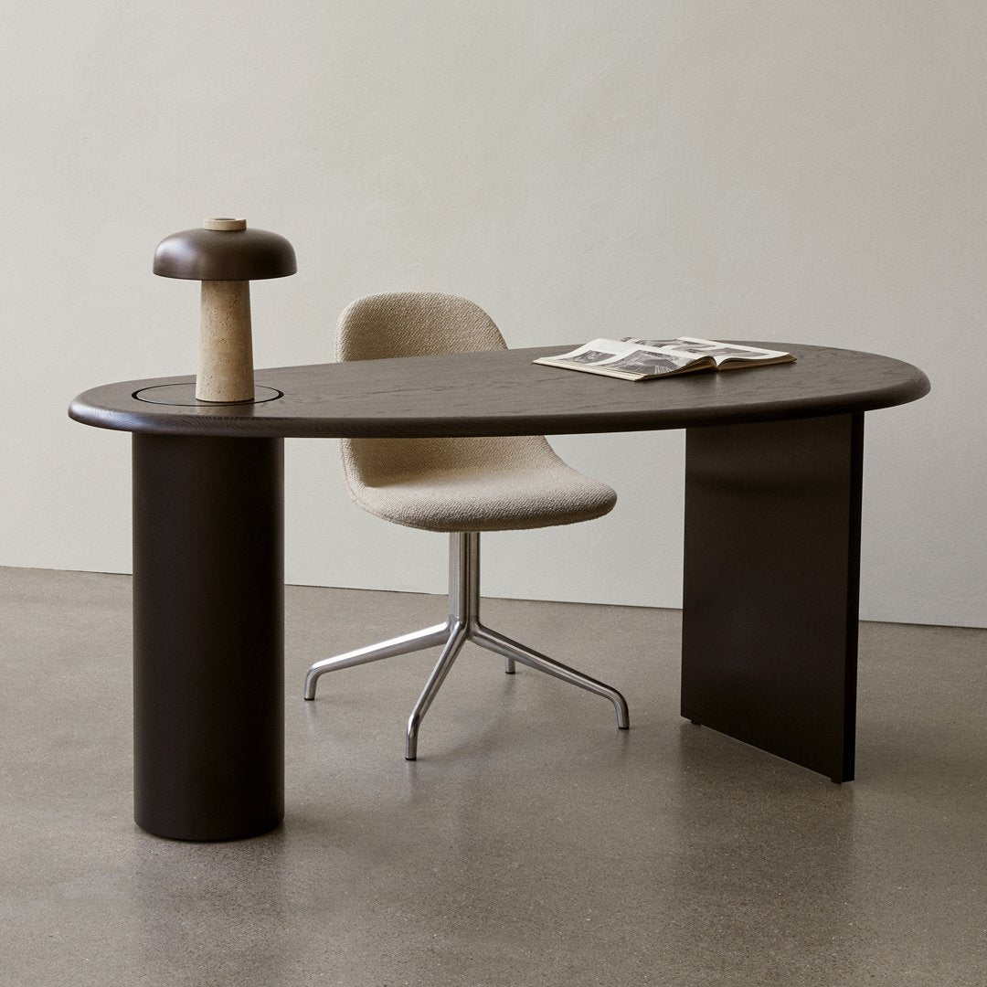 Brown oval desk with textured dark brown accents and a light beige chair on a gray floor background.
