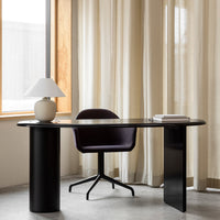 Modern black desk with a purple chair, paired with soft beige curtains and a white lamp for a minimalist aesthetic.