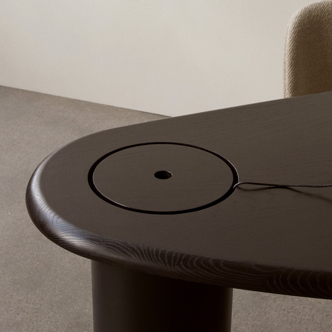 Dark wooden table with smooth, rounded edges and a circular cutout, showcasing rich grain patterns and a minimalist design.