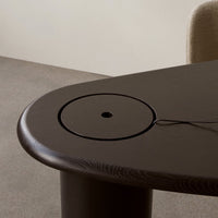 Dark wooden table with smooth, rounded edges and a circular cutout, showcasing rich grain patterns and a minimalist design.