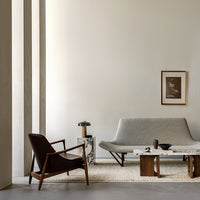 Modern living room featuring grey sofa, brown leather chair, marble accents, and neutral tones throughout.