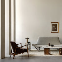 Mid-century modern living room featuring neutral tones, warm wood accents, and a textured rug pattern.
