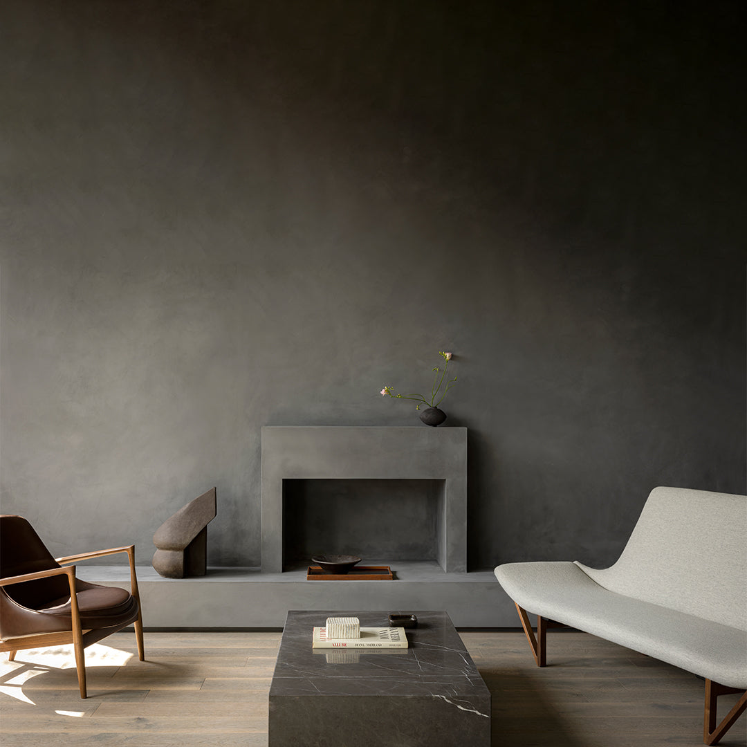 Modern interior featuring a dark gray wall, charcoal accents, and a light gray sofa against warm wood tones.