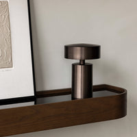 "Sleek bronze pot with a minimalist design on a wood shelf, muted tones and smooth finish."