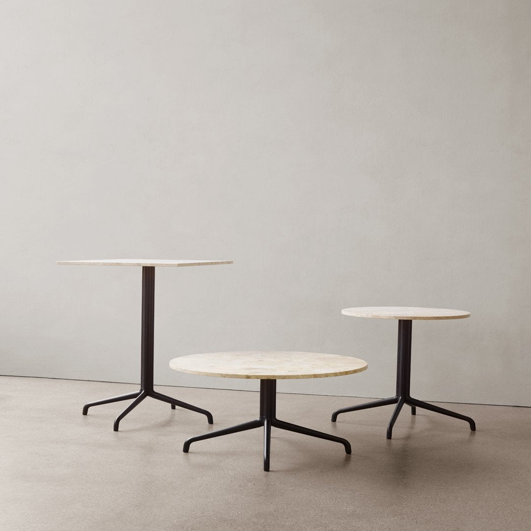 Three modern tables with round white marble tops and sleek black metal legs, featuring a minimalist design.