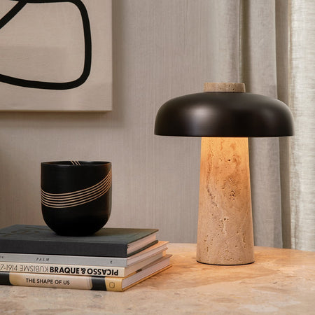 Black modern lamp with a textured beige base, accented by a sleek gold and black striped ceramic cup.