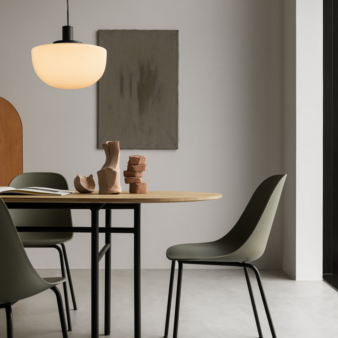 Modern dining space featuring an ivory pendant light, olive green chairs, and neutral tones with earthy textures.