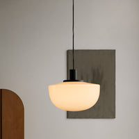 Modern pendant lamp with a soft white glass shade and black accents, suspended against a neutral background.
