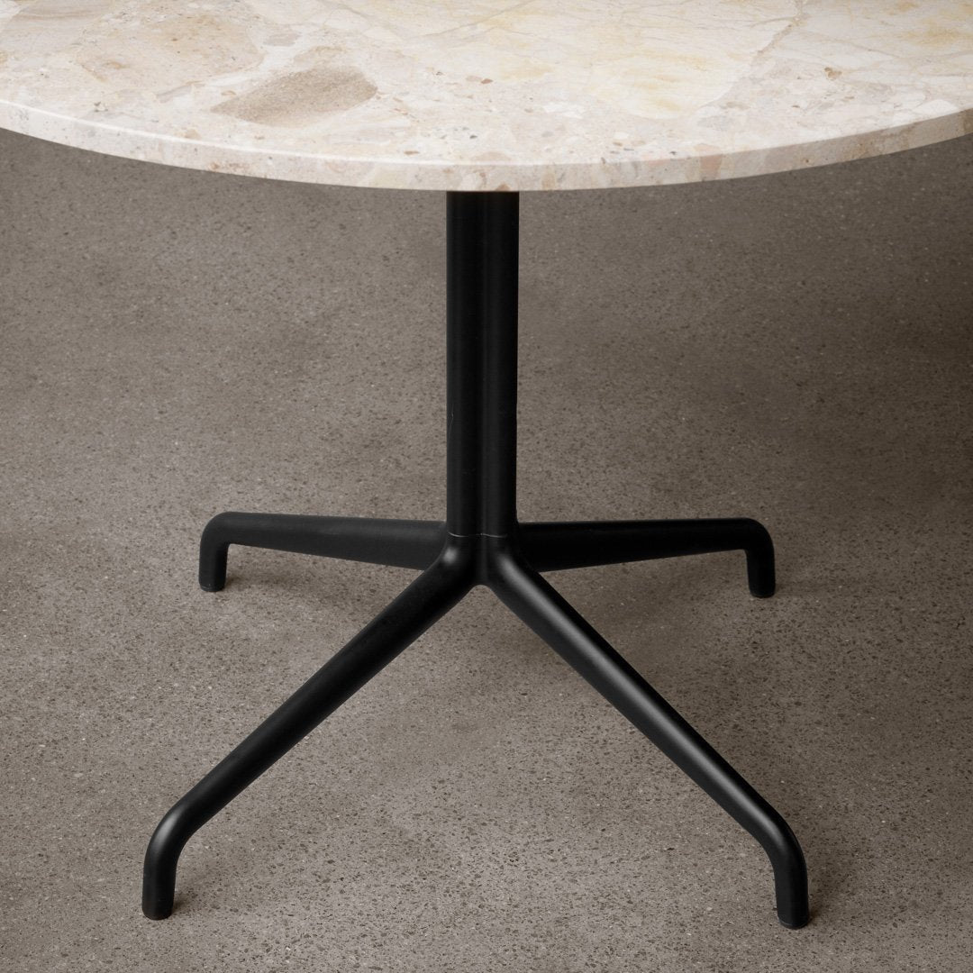 Round marble tabletop with subtle beige and cream patterns, supported by a sleek black metal base. Perfect for modern decor.