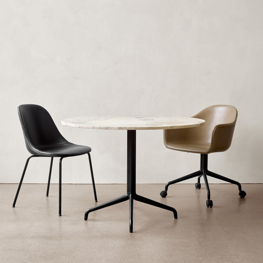 Black and tan chairs with a round white marble table on a neutral background. Modern minimalist design.