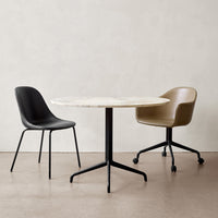 Black and tan chairs with a round white marble table on a neutral background. Modern minimalist design.