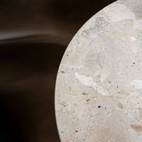 Round beige stone table with subtle patterns and speckles against a dark background. Ideal for modern decor.