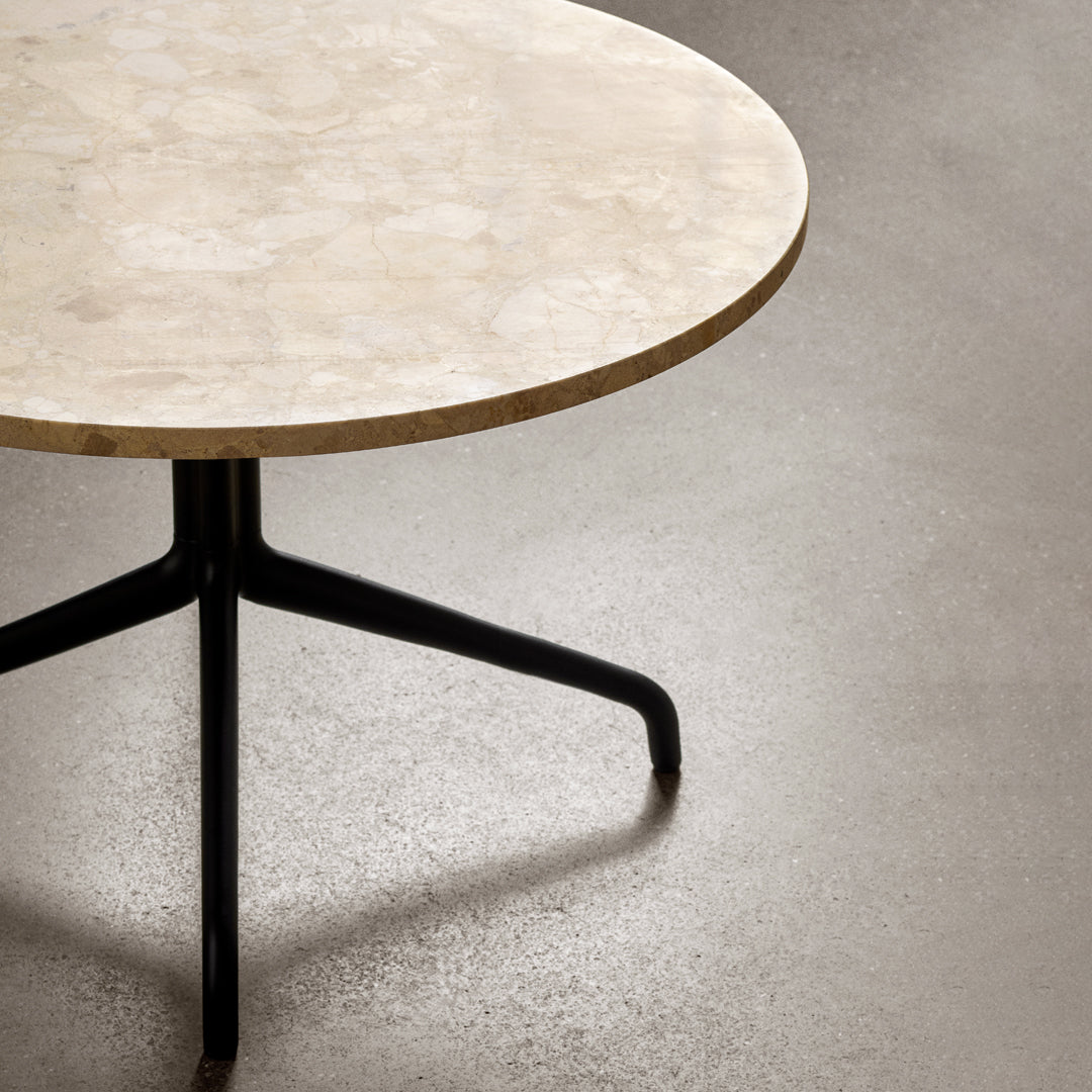 Round marble tabletop in a soft beige hue, featuring a sleek black metal base for a modern aesthetic.