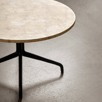 Round marble tabletop in a soft beige hue, featuring a sleek black metal base for a modern aesthetic.