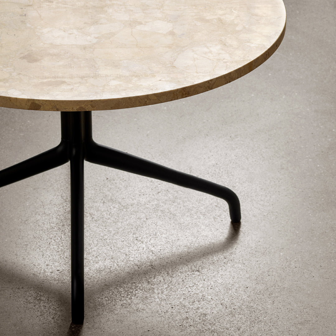 Round table with a beige marble top and sleek black metal legs, showcasing a modern and minimalist design.