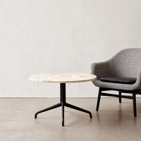 Round marble coffee table with a creamy white pattern and sleek black metal legs, paired with a textured gray chair.