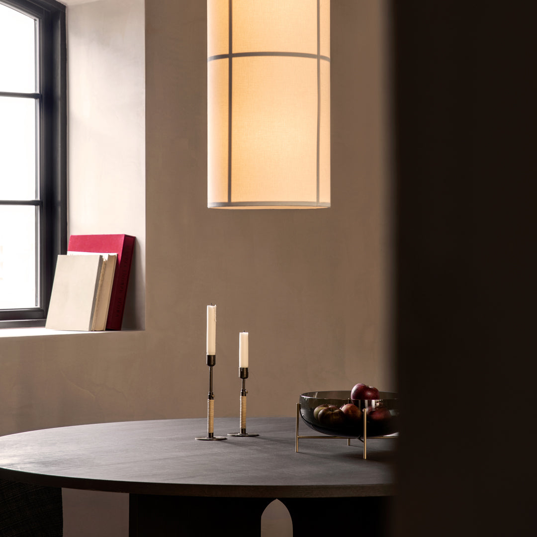 Modern dining room decor featuring warm beige walls, black table, cream candles, and a soft, warm lamp glow.