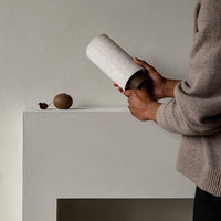 Neutral-toned ceramic vase with a textured, speckled pattern, placed on a minimalist light gray surface.
