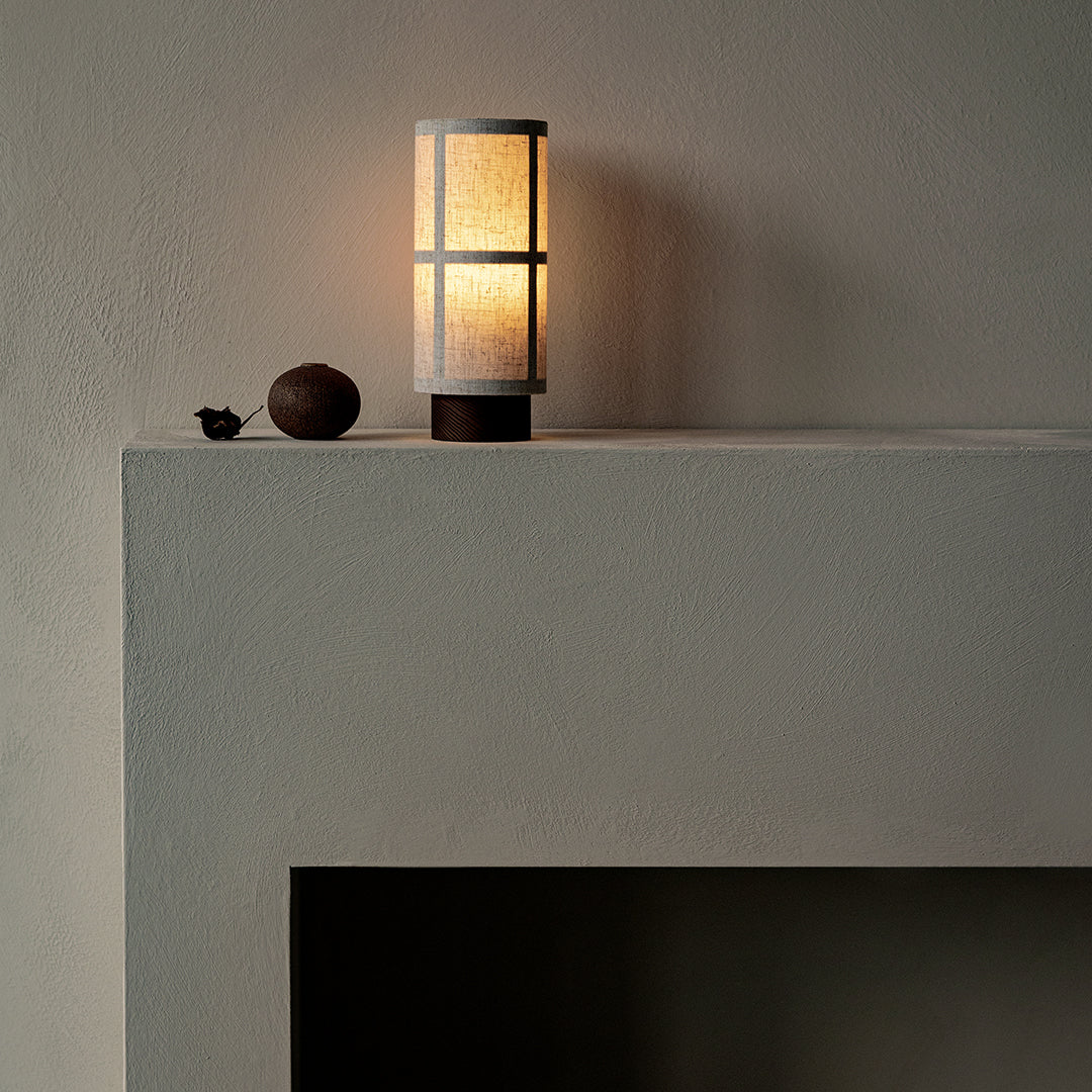 Minimalist beige lamp with a soft glow, featuring a textured white shade and a dark brown base.