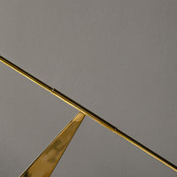 Gold geometric metal design on a soft gray background, showcasing sleek lines and modern elegance.