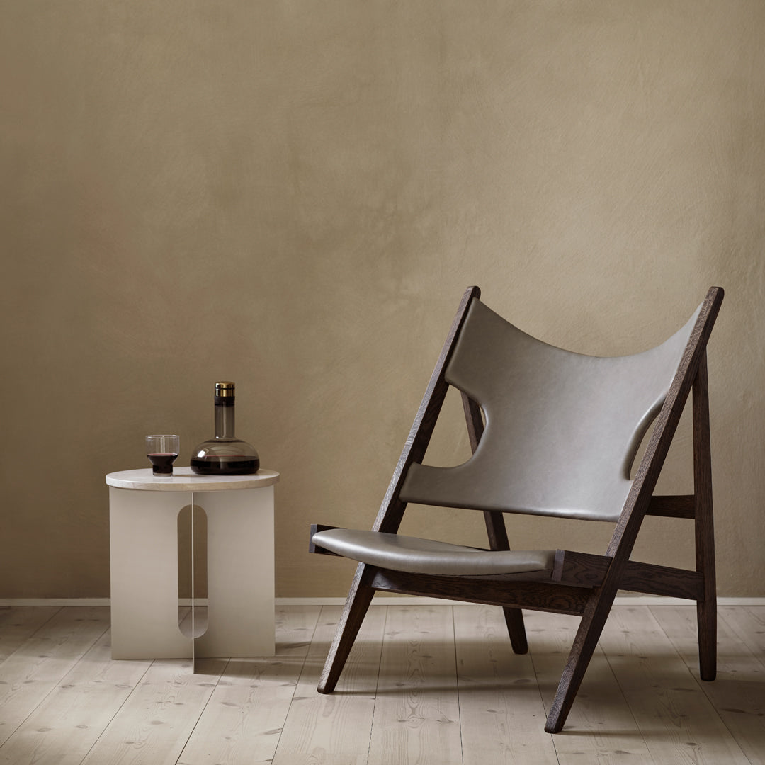 Stylish lounge chair with gray fabric and dark wooden frame, paired with a minimalist white side table.