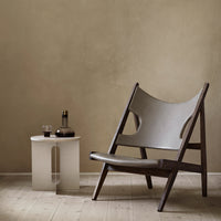 Stylish lounge chair with gray fabric and dark wooden frame, paired with a minimalist white side table.