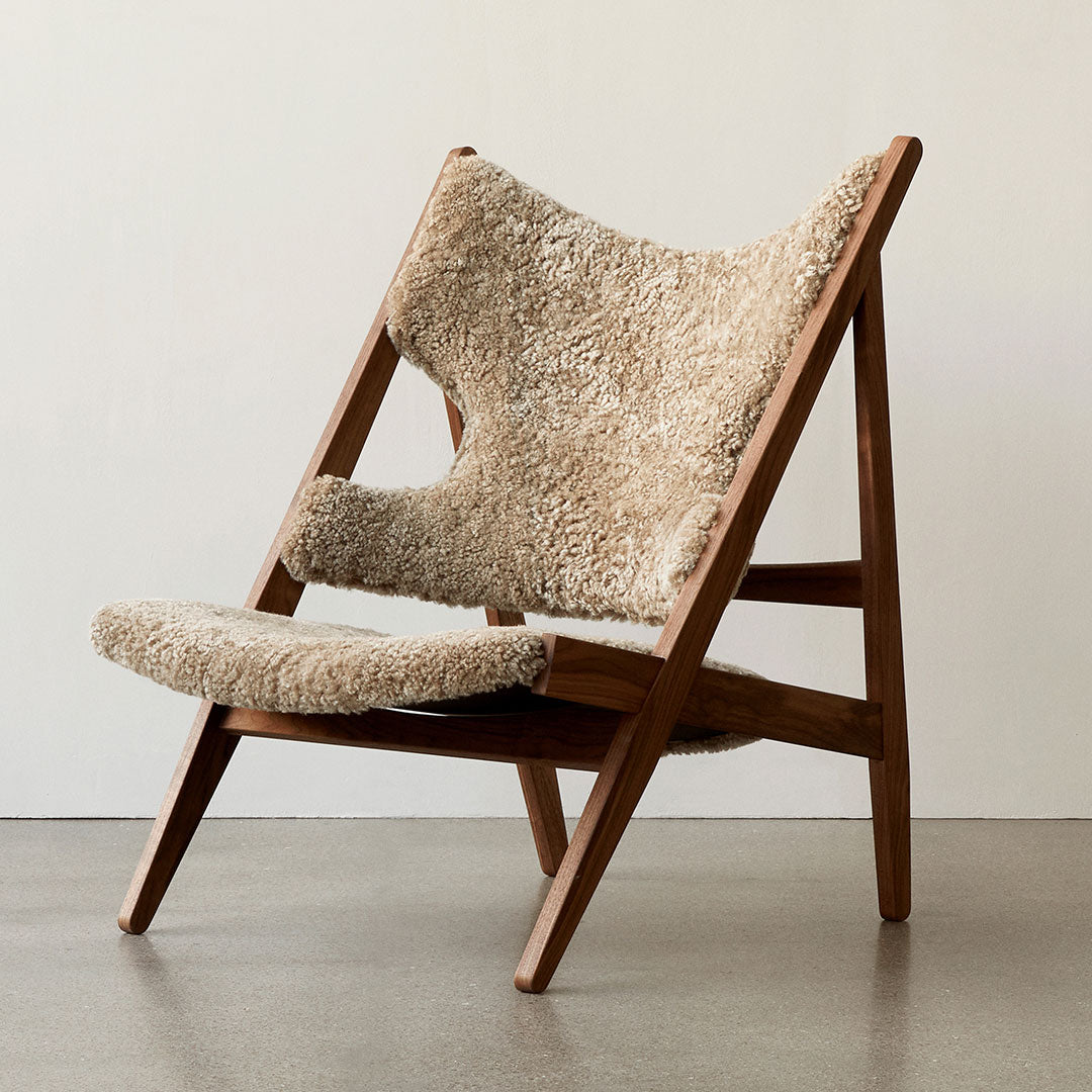 Beige and soft cream patterned upholstery on a wooden-framed chair, featuring a minimalist design and natural textures.