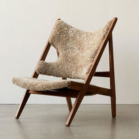 Beige and soft cream patterned upholstery on a wooden-framed chair, featuring a minimalist design and natural textures.