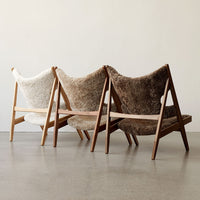 Three stylish chairs featuring cozy textures in white, light brown, and dark brown hues against a neutral background.