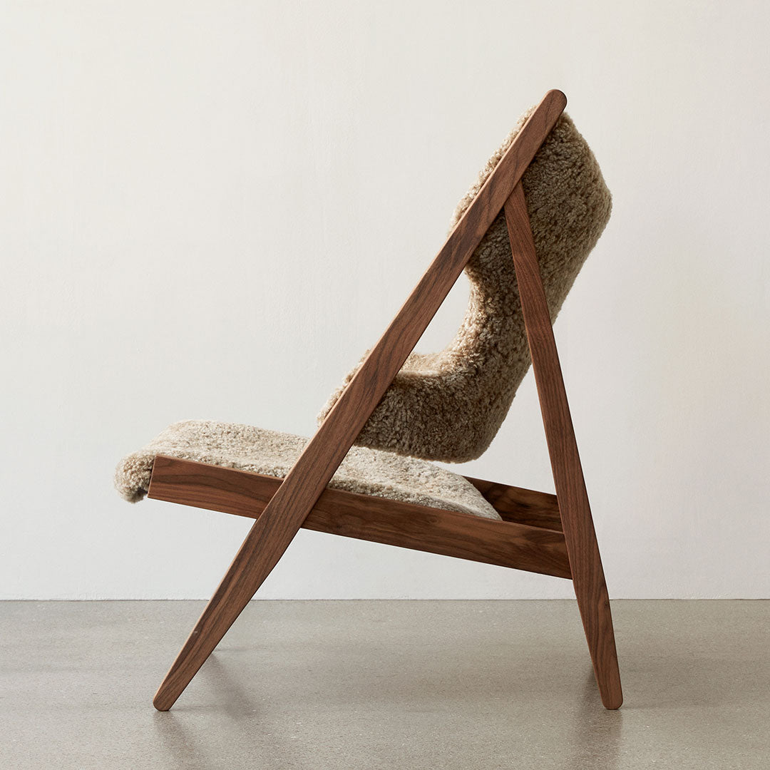 Light beige upholstered chair with a textured surface and warm wooden frame, showcasing a modern, minimalistic design.