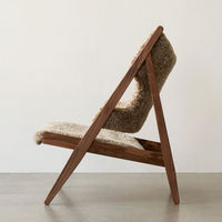 Light beige upholstered chair with a textured surface and warm wooden frame, showcasing a modern, minimalistic design.