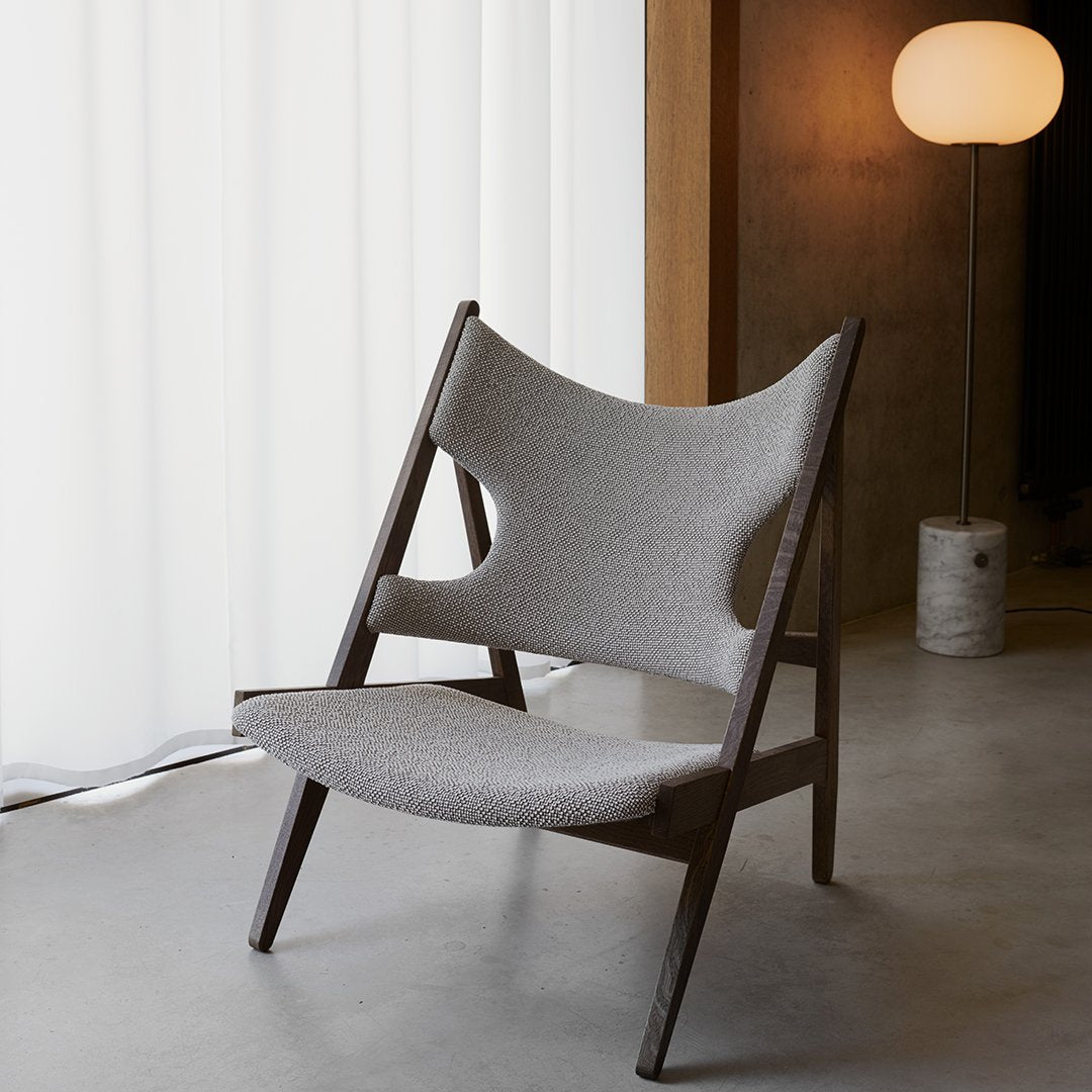 "Modern gray chair with unique cutout pattern and dark wood frame, featuring a minimalist design."