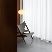 Gray-patterned chair against a backdrop of white curtains and warm wood tones, showcasing minimalist design aesthetics.