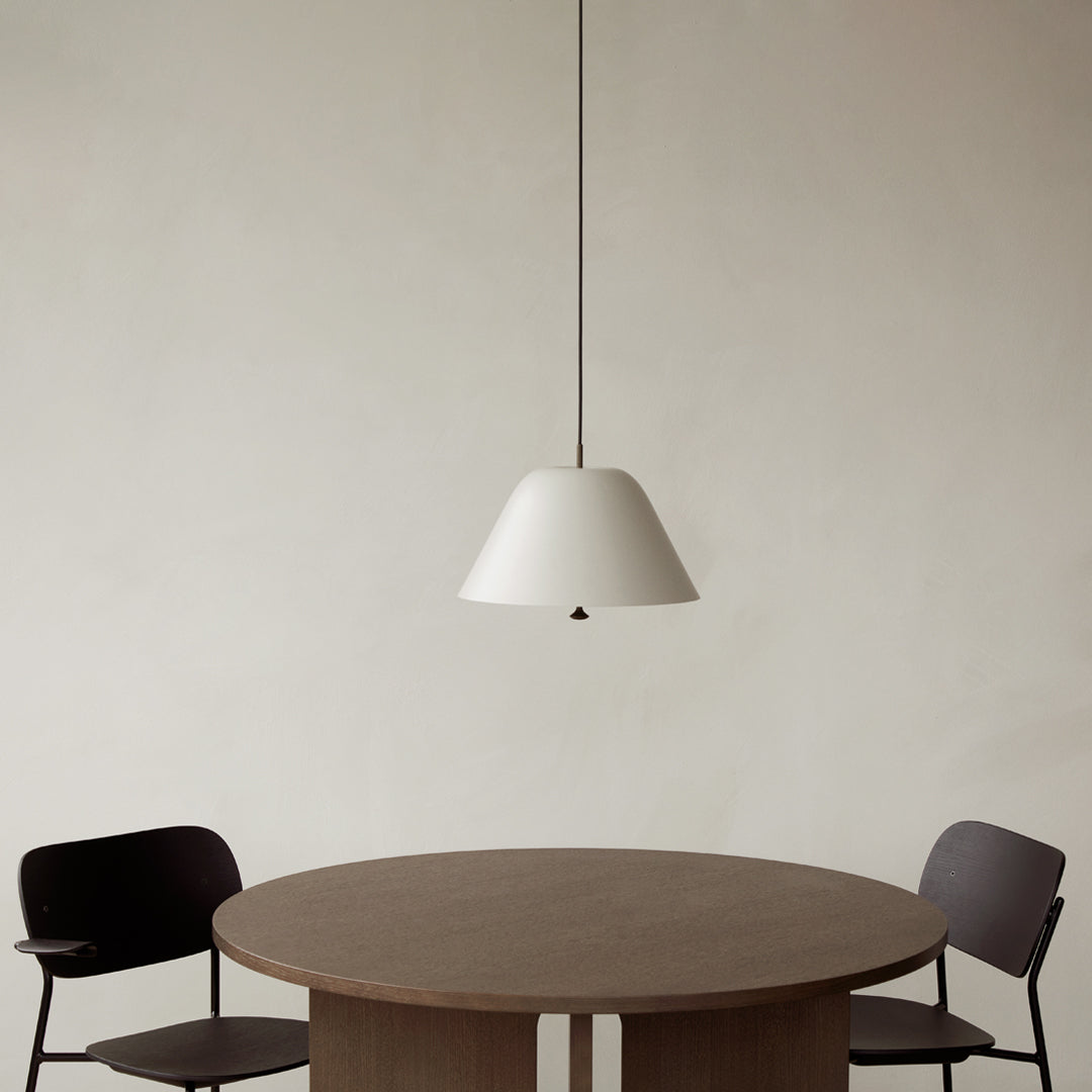 White pendant lamp above a round wooden table, paired with sleek black chairs against a neutral background.