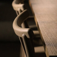 Light wooden dining table with smooth, natural grain patterns and elegant, curved chair details.