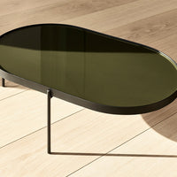 Black metal coffee table with a smooth olive green top, set against a light wooden floor.