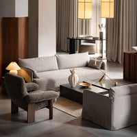 Neutral gray sofa, brown textured chair, warm beige curtains, and gold accents create a modern, cozy living space.