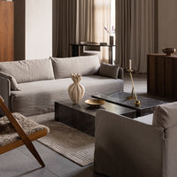Neutral beige sofa with textured cushions, dark marble table, and soft gray area rug, creating a modern and calming aesthetic.