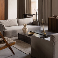 Grey textured sofas with a dark marble table, beige vase, and neutral curtains create a cozy, modern living space.