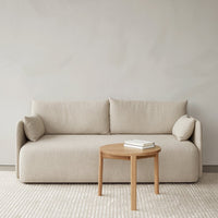 Beige sofa with textured fabric, complemented by light wooden table and soft, neutral-toned rug. Modern minimalist design.