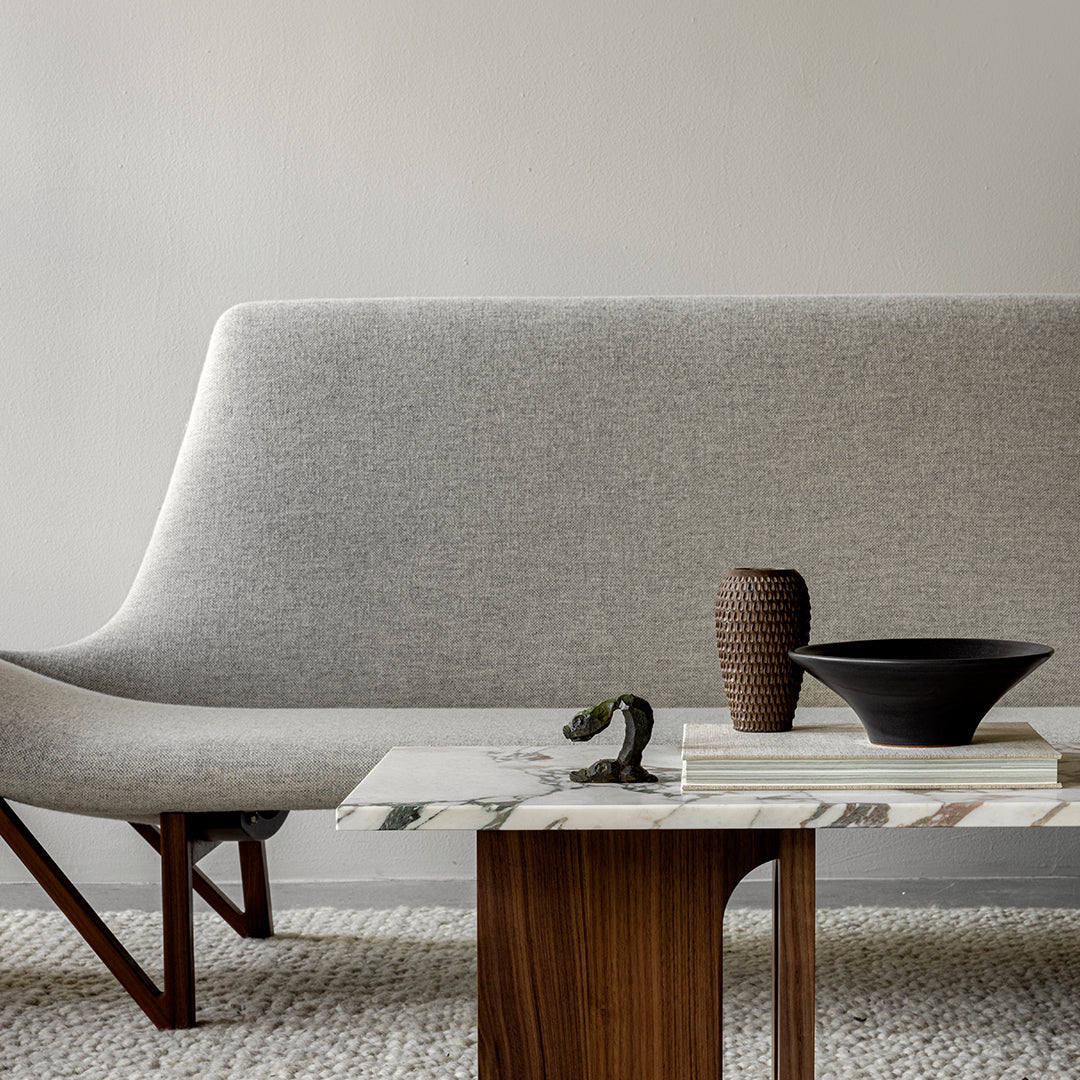 Gray upholstered sofa with a soft texture, marble coffee table featuring green and white patterns, and earthy brown accents.