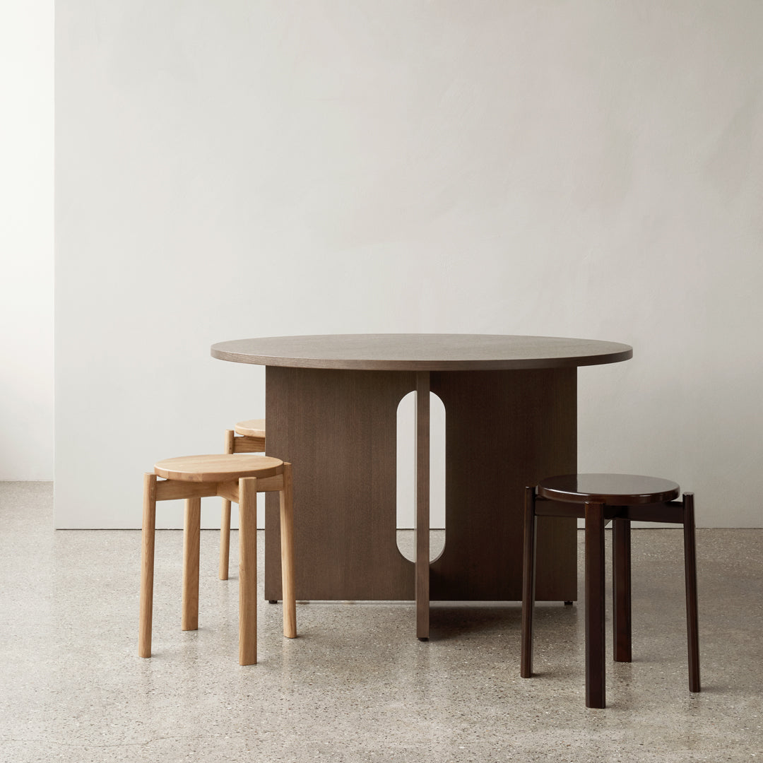 Round wooden dining table with a sleek, minimalist design; features dark brown and light wood tones.