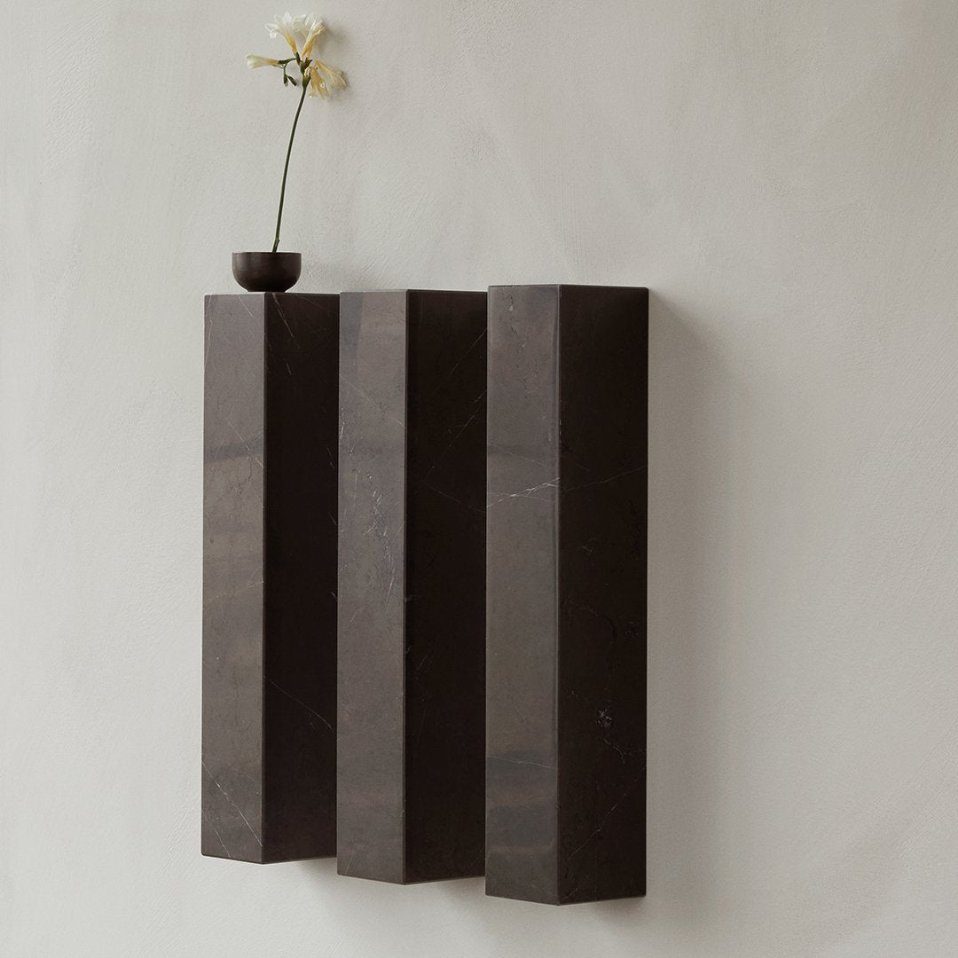 Dark gray rectangular wall sculpture with subtle veining, contrasting against a light textured background.