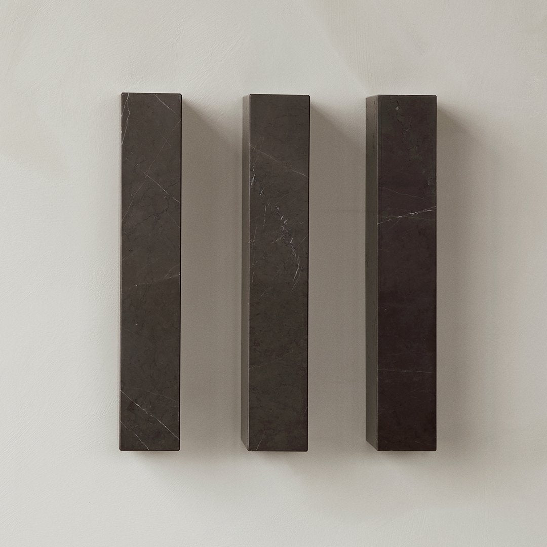 Three dark gray marble blocks with subtle veining against a light textured background. Elegant and modern design.