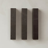 Three dark gray marble blocks with subtle veining against a light textured background. Elegant and modern design.