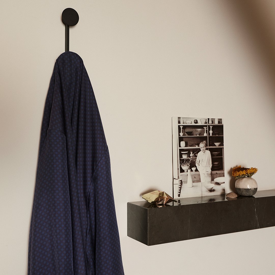 Navy blue robe with subtle diamond pattern, hanging against a light wall, accentuated by a sleek black hook.