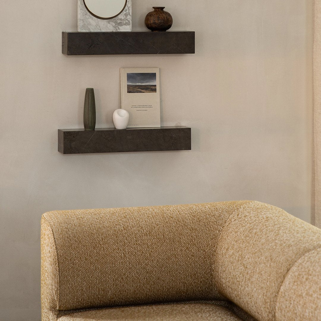 Textured yellow and cream sofa with dark floating shelves and neutral wall for modern interior design.