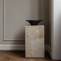Neutral beige stone pedestal with subtle speckles and a dark, elegant vase. Modern design for sophisticated decor.