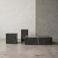 "Elegant black marble coffee table set with striking white veining on a minimalist concrete background."